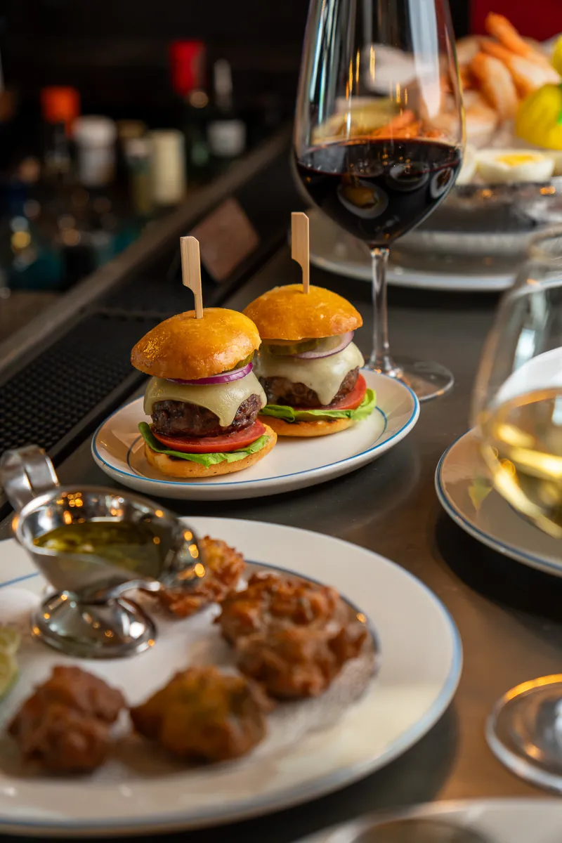 Cheeseburger sliders, salt cod fritters and garlic aioli on the bar at apéro