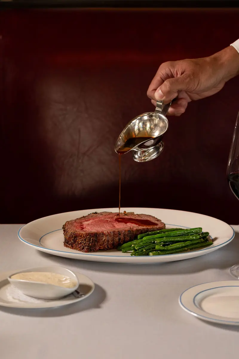Au jus poured from a silver sauce boat