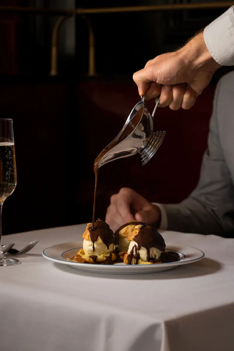 Warm chocolate sauce poured over profiteroles