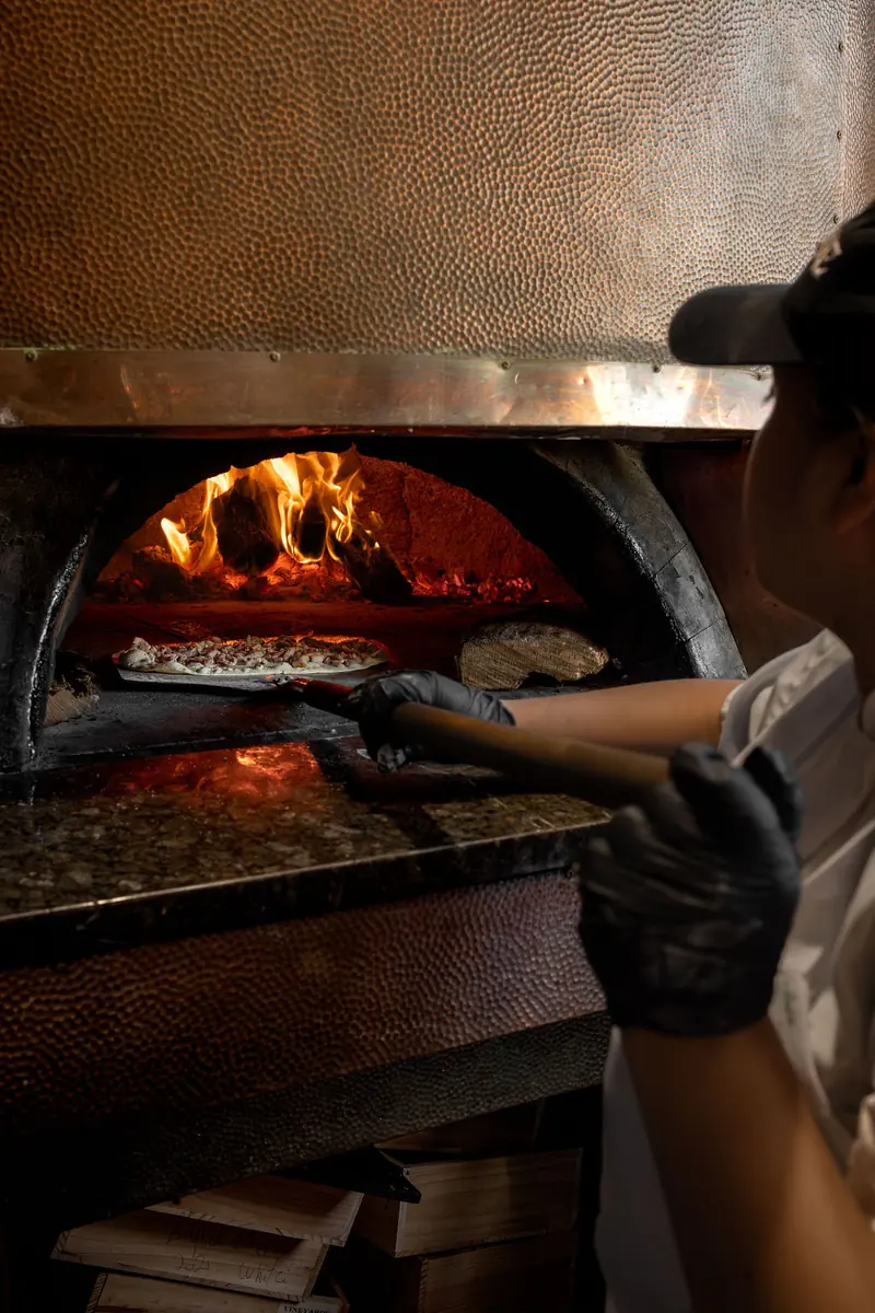 A tarte flambée coming out of the wood-fired oven